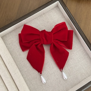Detail of red velvet bow hair clip with elegant pearl teardrop pendants on wooden background