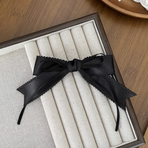 Vue détaillée d'un serre-tête en satin noir avec bords en dentelle sur un coffret