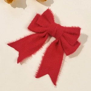 Detail of red plush bow hair clip featuring soft faux mink fur texture for winter