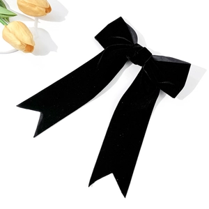 Detailed close-up of a premium black velvet bow hair clip with elegant long ribbons