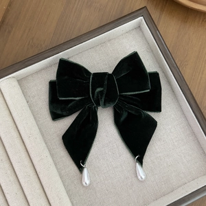 Close-up of a dark green velvet bow hair clip with elegant white pearl pendants