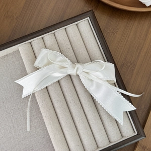 Détail d'une pince à cheveux nœud en satin crème avec bordure en dentelle