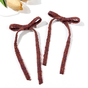 Detail of dark red knitted bow hair clips with long ribbons and metal duckbill clips