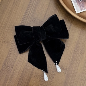 Detail of a vintage black velvet bow hair clip with elegant white pearl teardrop pendants