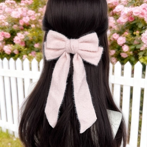 Detail of pink wool bow hair clip with ribbons on woman hair in garden setting