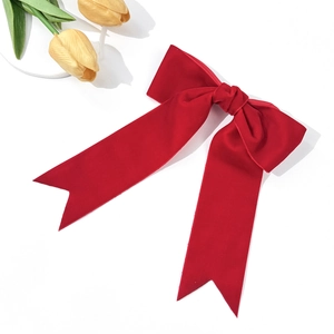 Detailed view of red velvet bow hair clip with double streamers on white background