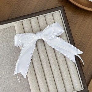 Vue détaillée d'une barrette nœud blanc avec bords en dentelle sur boîte à bijoux