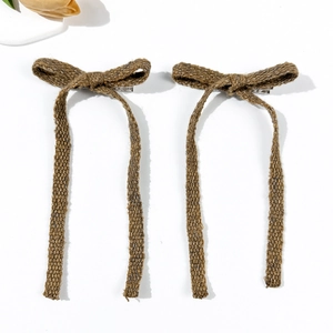 Close-up of two brown knitted bow hair clips with long ribbons and metal duckbill clips