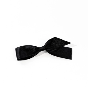 Detailed close-up of premium black satin bow hair clip with fine twill texture and silk sheen