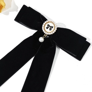 Close-up of velvet bow hair clip with pearl pendant and numbered metal emblem