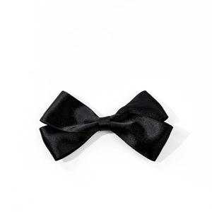 Detail of elegant black satin bow hair clip with glossy silk texture on white background