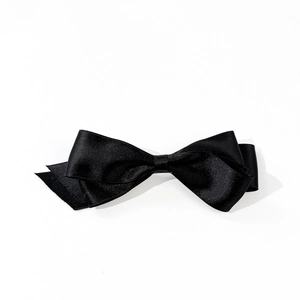 Macro detail of the elegant double-layered black satin texture on this hair bow clip