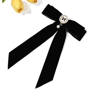 Detail of velvet bow hair clip with pearl pendant and elegant floral accents