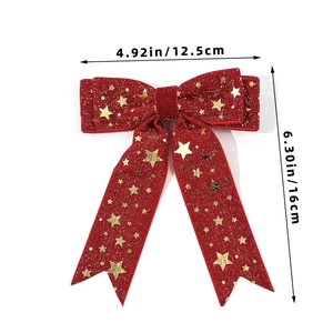 Detalle de lazo navideño de terciopelo rojo con estrellas doradas y medidas 12,5x16 cm