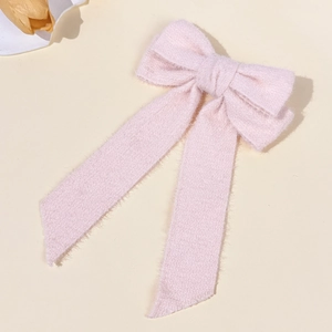 Close-up of a pink wool bow hair clip with elegant long ribbons and soft knit texture