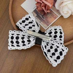 Detail of hollow lace bow hair clip with black ribbon and silver metal duckbill clip
