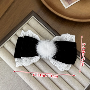 Detailed size view of black velvet and lace bow hair clip with plush ball in center