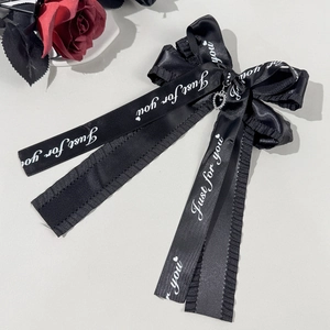 Détail de la pince à cheveux noeud en satin noir avec coeur strass et texte imprimé