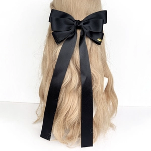 Détail d'une élégante pince à cheveux nœud en satin noir avec de longs rubans