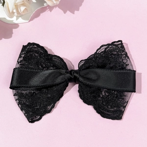 Detailed view of large black lace bow hair clip with satin ribbon and floral pattern