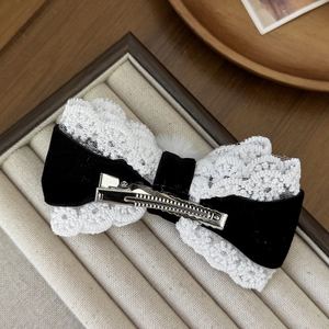 Elegant black velvet and white lace bow hair clip with faux fur ball on a tray