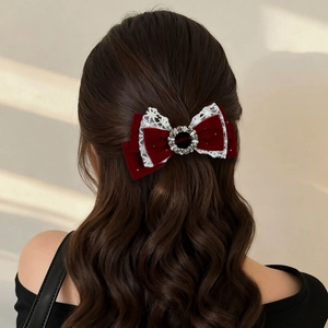 Detail of burgundy velvet bow hair clip with white lace trim and rhinestone center on hair
