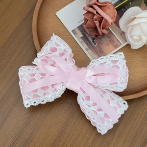 Detailed macro view of the delicate white lace trim on the pink satin bow hair clip