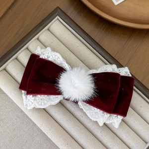 Close-up of velvet lace bow hair clip with white faux fur ball in a jewelry box