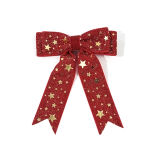 Detalle de lazo navideño de terciopelo rojo con motivos de estrellas doradas