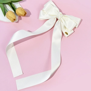 Grande pince à cheveux élégante en satin crème avec nœud papillon et rubans sur fond rose