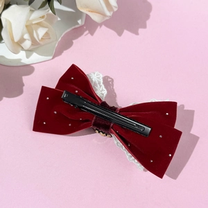 Velvet bow hair clip in wine red with lace trim and rhinestones on pink background