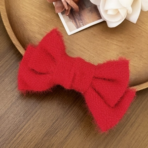 Dettaglio ravvicinato di un fermaglio per capelli con fiocco rosso peluche su legno