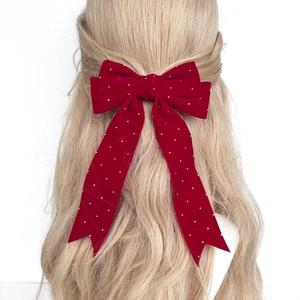 Close-up of a burgundy velvet bow hair clip with sparkling rhinestones on long ribbons