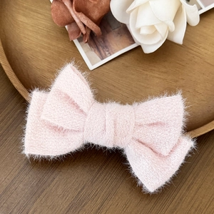 Dettaglio di un fermaglio per capelli a fiocco in tweed rosa su piatto di legno