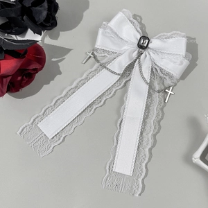 Détail d'une pince à cheveux en dentelle blanche avec chaînes, croix et pierre sombre