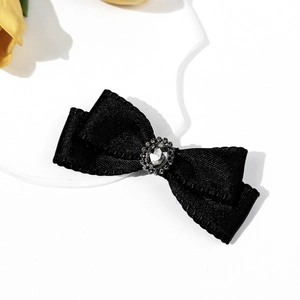 Close-up of black ribbon bow hair clip with vintage crystal center and floral accent