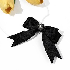 Detail of black satin bow hair clip with a large faceted rhinestone and crystal border