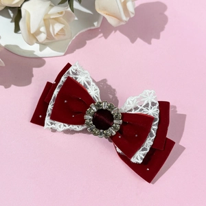 Detail of red velvet and white lace hair clip with a centered rhinestone buckle