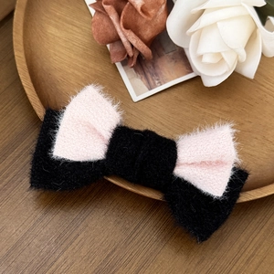 Dettaglio di un fermaglio per capelli a fiocco in velluto rosa e nero su vassoio in legno