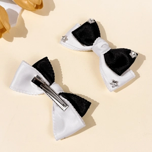 Elegant black and white bow hair clips with crystal stars on a minimalist beige background