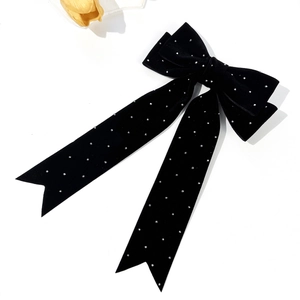 Detailed view of black velvet bow hair clip with silver rhinestones and long streamers
