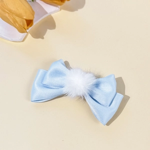 Detailed view of light blue satin ribbon hair clip featuring a soft white fur ball accent