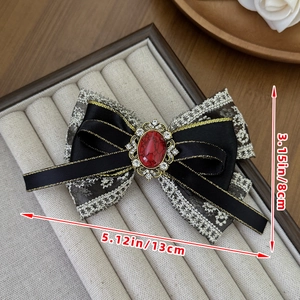 Detail of vintage lace bow hair clip with red gemstone and crystal trim 13x8cm