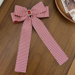 Macro view of red houndstooth bow hair clip with central ruby and sparkling rhinestones