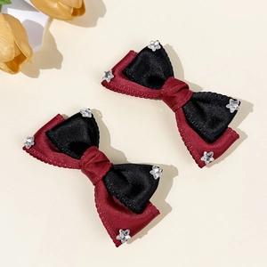 Two-piece red and black ribbon bow hair clips with star charms on a beige background