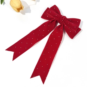 Detailed view of red velvet bow hair clip with sparkling rhinestones and long streamers