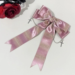 Détail du nœud papillon rose pailleté avec chaînes argentées et pendentifs croix