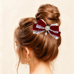 Close-up of velvet lace bow hair clip and gold pearl hoop earrings on model