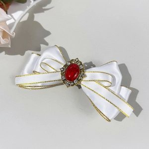 Close-up of white satin bow hair clip with vintage red gemstone and gold-tone details