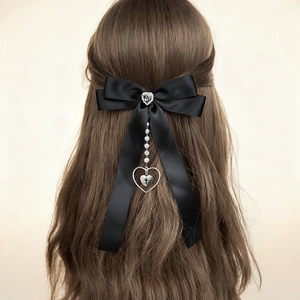 Détail de la pince à cheveux nœud satin noir avec perle et cœur sur cheveux bouclés